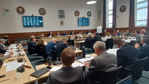 LDRS A full council meeting with lots of people in suits and smart dress in a meeting room