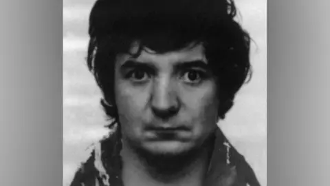 Merseyside Police A black-and-white police mugshot of Peter Sullivan, taken in 1986. In the photograph he has black bushy hair and is wearing a woolly coat.