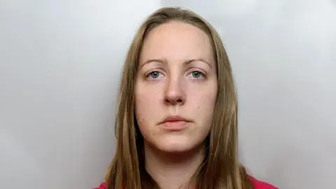 Cheshire Police Mugshot of Lucy Letby in red hoody - long brown hair and thin eyebrows