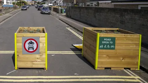 Wooden bollards preventing any motor traffic to Cowley Road as part of a low-traffic neighbourhood.