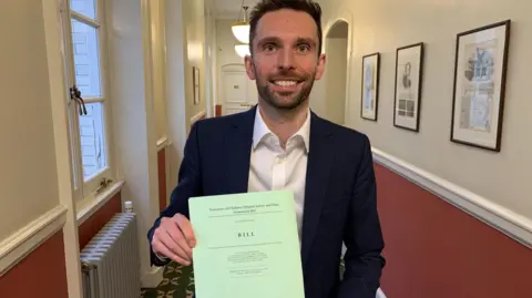 Hamish Phelan MP Josh MacAlister holding up a copy of the draft bill