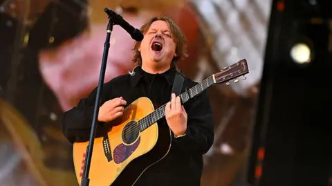 Getty Images Lewis Capaldi playing guitar and singing on stage