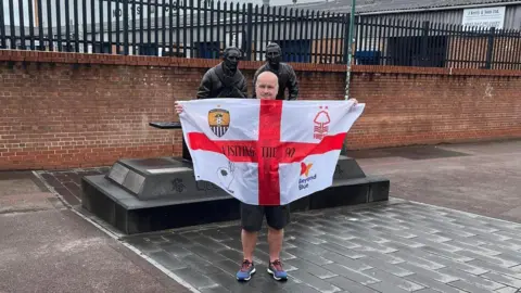 Stephen Roome Mr Roome holding an England flag with emblems for mental health charities, Nottingham Forest FC and Notts County FC 