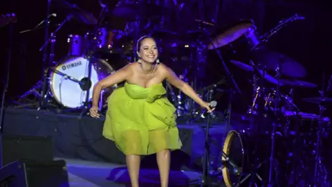 AFP Tunisian singer Noor Arjourn singing in a green dress on stage. There are drums behind her in Carthage, Tunisia - Wednesday 27 July 2022