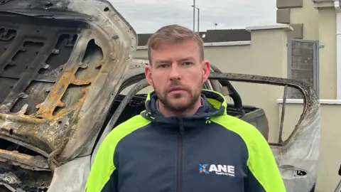 Nathan Kane stood beside burned out car