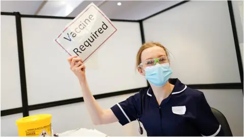 Getty Images Nurse holding sign - vaccine required