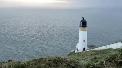 Maughold lighthouse, which sits on the edge of a cliff with the Irish Sea stretching out in front of it.