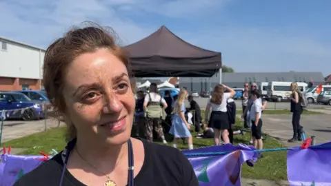 Andrew Turner/BBC Taraneh Jahanpour standing by some flags made by children