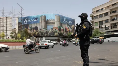 WANA via Reuters A security guard stands on a street in Tehran, Iran, during early hours of ceasefire between Iran and Israel