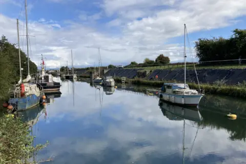 Some boats moored on both sides of Lydney Harbour, with blue skies overhead