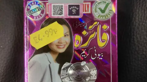 A price tag on a product, with a woman's face on it, with writing in a foreign language. It has a £4.99 yellow price sticker on it. 