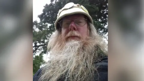 Monster Raving Loony Party The Baron has a long grey beard and is photographed outside wearing a beige coloured pith helmet