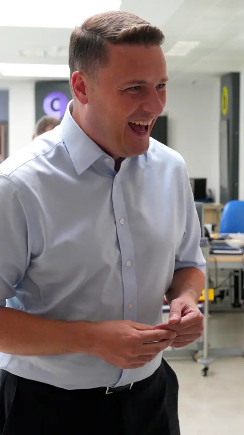 Health Secretary Wes Streeting in shirt sleeves smiling in a hospital ward