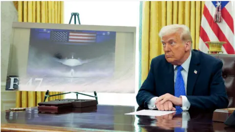 Donald Trump sitting next to an image of the F-47 in the Oval Office