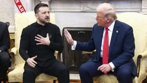 EPA Sitting on gold chairs in the Oval Office, Zelensky, left, holds a hand to his chest as he speaks, while Trump, right, holds a hand up to Zelensky as he also speaks