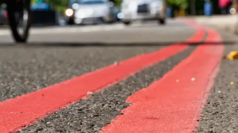 Reading Borough Council A close up of double red lines painted at the edge of a road.