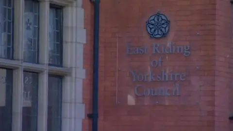 The outside of East Riding of Yorkshire Council building, a light-coloured , brick building with large signage on the side