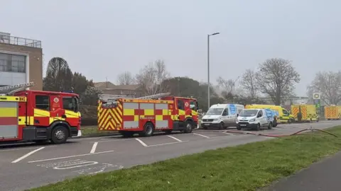 Rhianna Venables/BBC Fire crews and ambulances parked on the road outside an industrial area.