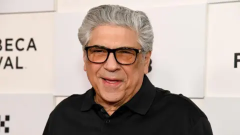 Vincent Pastore wears a black polo shirt and black-rimmed glasses.