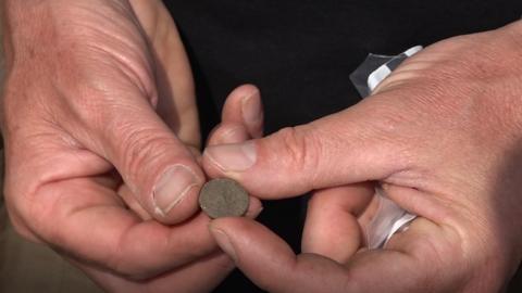 An archaeologist holds an ancient gold coin dating back to the late 4th century AD