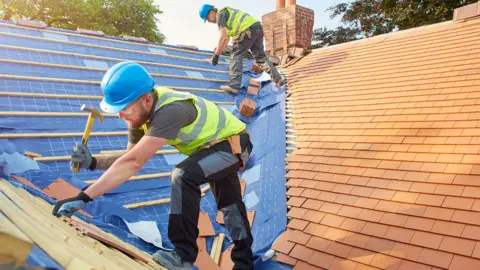 Getty Images Workers tiling a roof