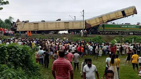 Getty Images Des personnes observent le lieu d'une collision entre un train express de voyageurs et un train de marchandises à Nirmaljote, près de la gare de Rangapani, dans l'État indien de West Bangal, le 17 juin 2024.