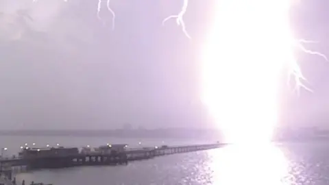 A huge lightning strike at the end of Southend Pier at night.