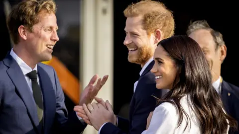 EPA Prince Harry, Duke of Sussex (C) and his wife, Meghan, Duchess of Sussex (R) arrive on the Yellow Carpet before the start of the Invictus Games in The Hague