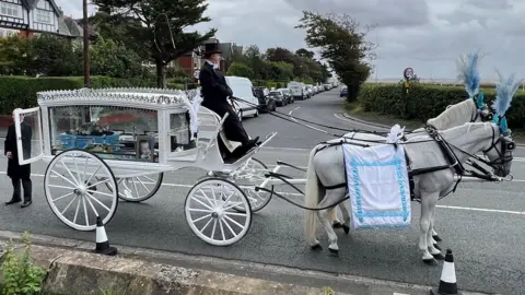 Damion's coffin was carried to the church in a white horse-drawn carriage