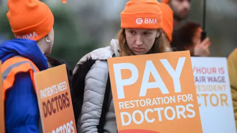 Resident doctors hold placards reading 'pay restoration for doctors' as they strike in London in November.