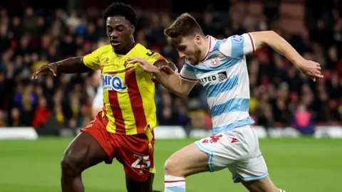 Wrexham midfielder George Thomason (right) runs beyond Watford's James Abankwah (left)