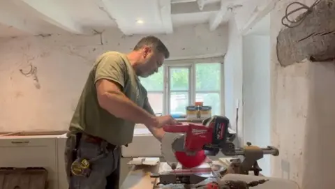 Matt uses a mechanised cutting tool in a carpenter's shed.