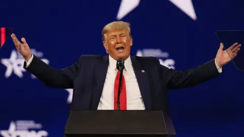 Getty Images Former President Donald Trump gestures with open arms at a conference in February