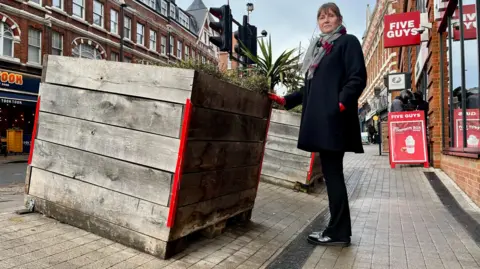 Sharon Hardwick Labour councillor Sharon Hardwick on the sloping pavement, near one of the planters which is on a slant