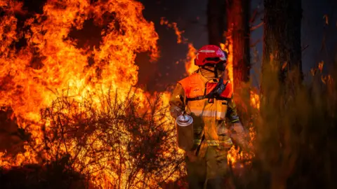 A firefighter works to contain a major wildfire near Saumos in France on 29 July.