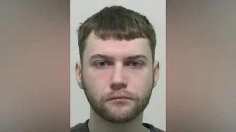 Mugshot of Tyson. He has a neat ginger beard and short dark hair.