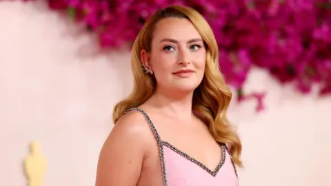 Getty Images Amelia Dimoldenberg in a pink dress against a floral background