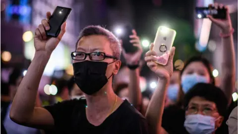 Getty Images Pro-democracy protesters hold up their mobile phone torches as they sing during a rally in the Causeway Bay district of Hong Kong on June 12, 2020