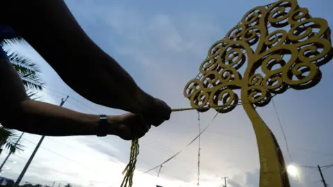 Getty Images Anti-government demonstrator tries to bring down the 'Tree of Life', metal sculptures erected across Managua as part of a city beautification plan by Vice-President and First Lady Rosario Murillo. 26 May 2018