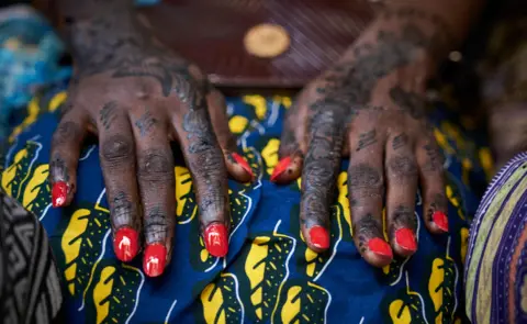 AFP A close shot of a woman's hands with henna and red nails