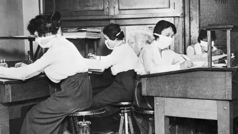 Bettmann/Getty Images Clerks wearing face masks at work during the Spanish flu pandemic in 1918