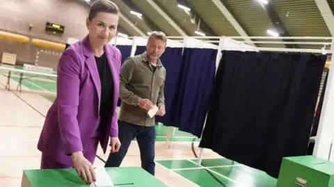 Getty Images Danish Prime Minister Mette Frederiksen, also leader of Denmark's Social Democrats, casts her ballot as her husband Bo Tengberg looks on at a polling station in Vaerloese near Copenhagen, Denmark, on June 1, 2022