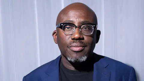 Edward Enninful pictured at Milan fashion week in September. Close up shot of head and shoulders, he's wearing a jacket and glasses