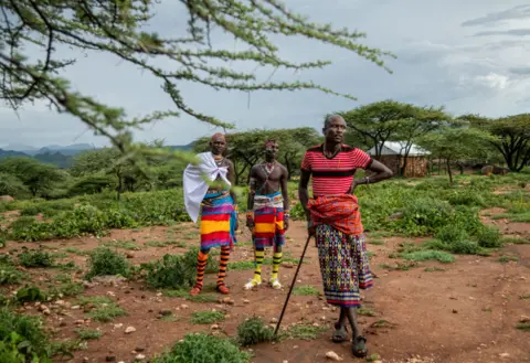 Georgina Smith/BBC Two Samburu warriors talk to Tiampati Leletit, who lost 80 of his goats when the locusts arrived