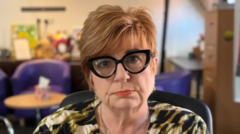 George King/BBC A head and shoulders image of Katherine Ahluwalia. She is wearing black glasses and sitting in a black chair. She is staring into the camera.