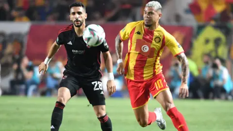 Al Ahly defender Fouad Karim fights for the ball with Esperance midfielder Yan Sasse