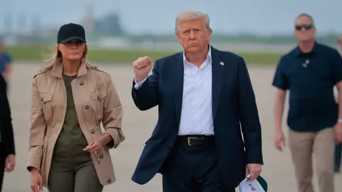 Donald Trump and First Lady Melanie land in Texas on Friday. Trump makes an upward fist motion as he looks at the camera