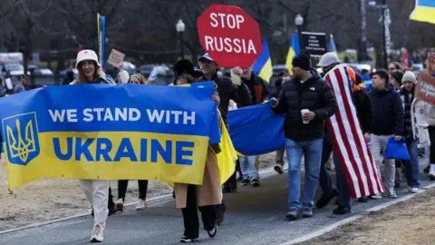 EPA-EFE/REX/Shutterstock A group of pro-Ukraine demonstrators including some holding signs reading "We Stand With Ukraine" and "Stop Russia", with one protesters draped in a US flag