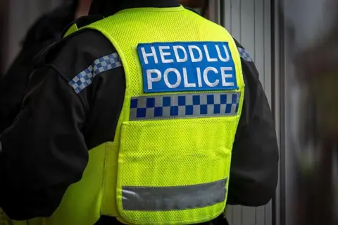 Getty Images The back of a policeman's hi-vis jacket. It says Heddlu/Police in white font.