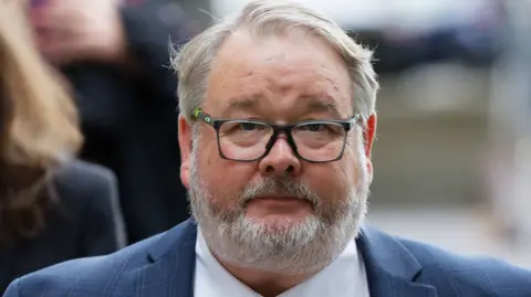 Christopher Mills, in a blue suit and tie